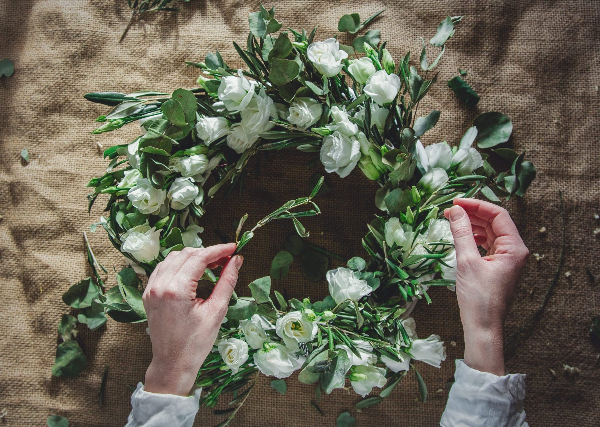 Wreath with white roses on jute background. Decorated